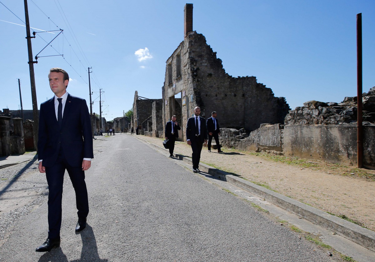 French President Emmanuel Macron (L) walks with officials after a ceremony to commemorate the 73rd anniversary of the Oradour-sur-Glane massacre, in the ruins of the martyrs village of Oradour-sur-Glane on June 10, 2017. (AFP / POOL / STEPHANE MAHE)