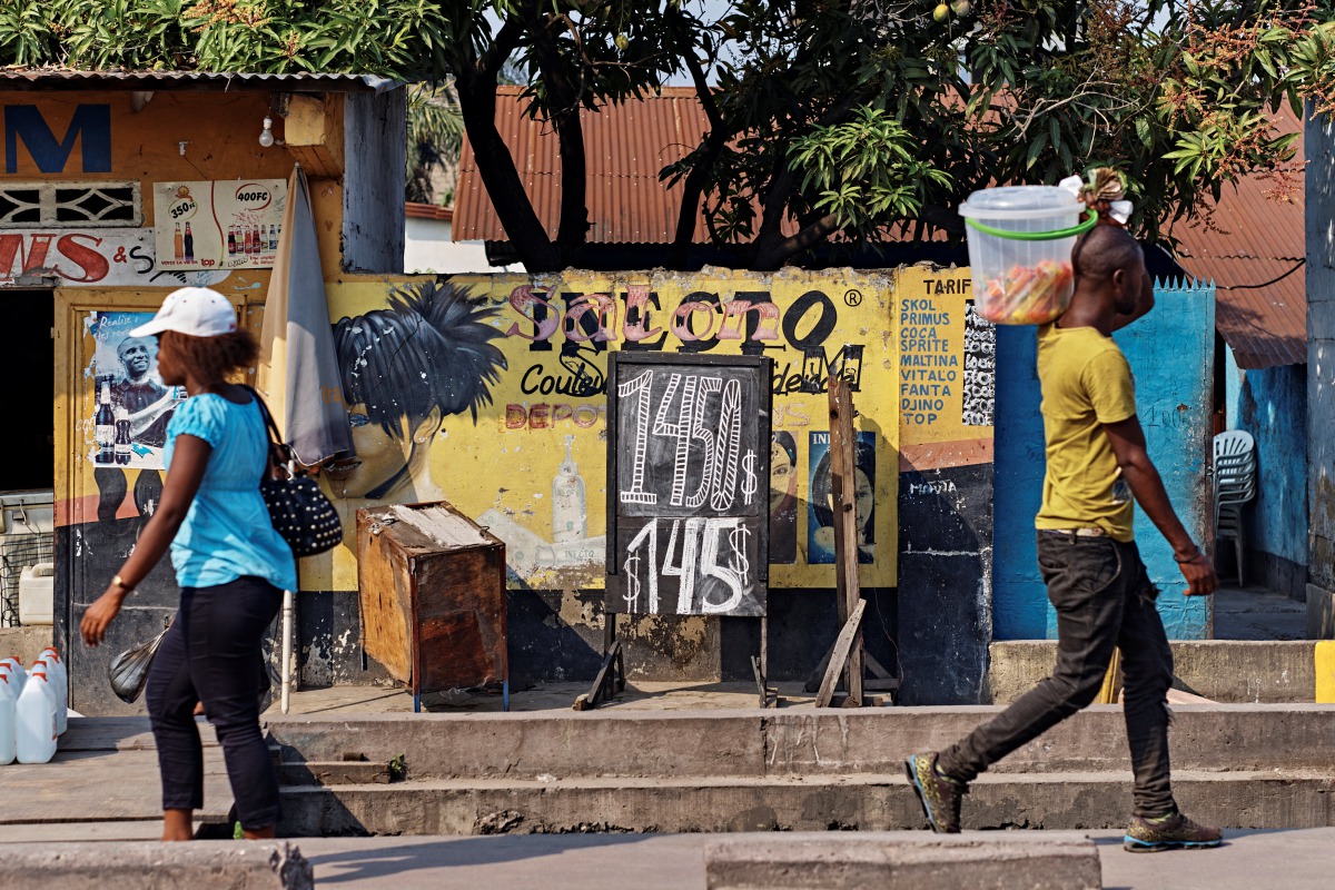 People walk in front of a store that advertises an exchange rate in Kinshasa, Democratic Republic of the Congo June 9, 2017. Picture taken June 9, 2017. (REUTERS/Robert Carrubba)