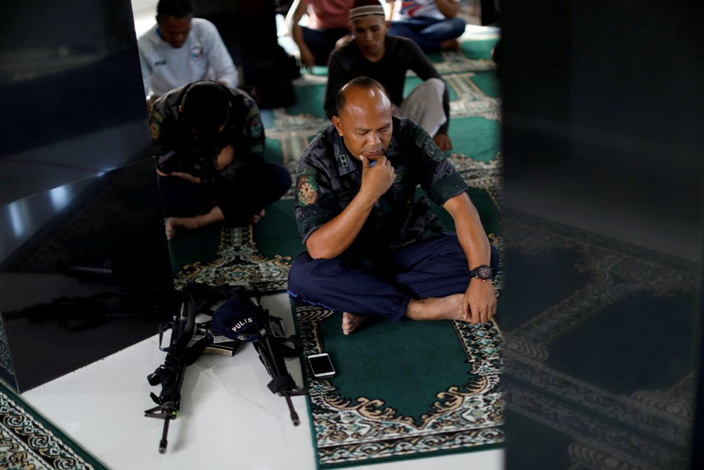 A Philippines police officer performs Eid al-Fitr prayers in a mosque inside the city hall compound in as government forces continue their assault against insurgents from the Maute group, who have taken over large parts of Marawi City , Philippines June 2