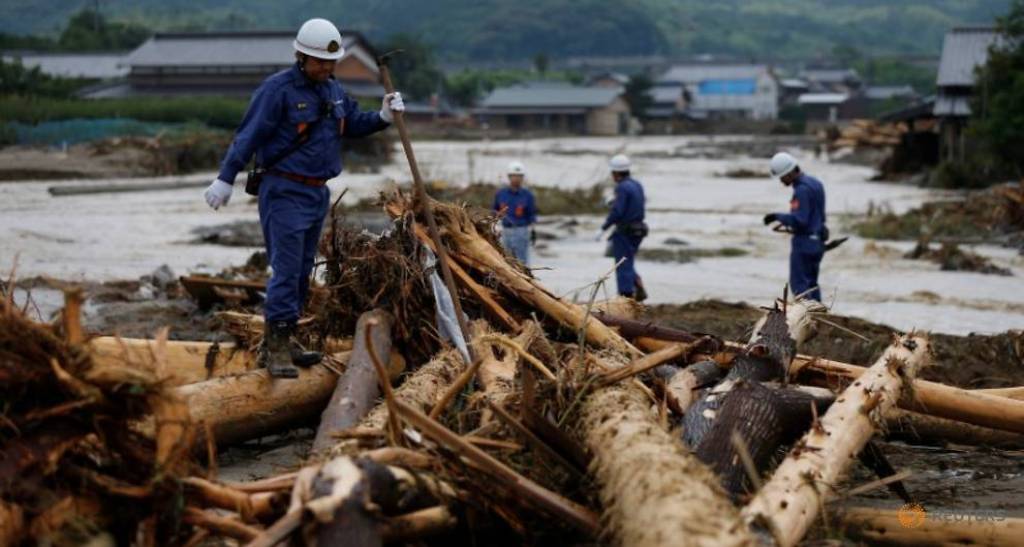 Police officers walk on woody debris which were swept by heavy rain as they conduct rescue and search operation in Asakura, Fukuoka Prefecture, Japan July 8, 2017. REUTERS/Issei Kato.