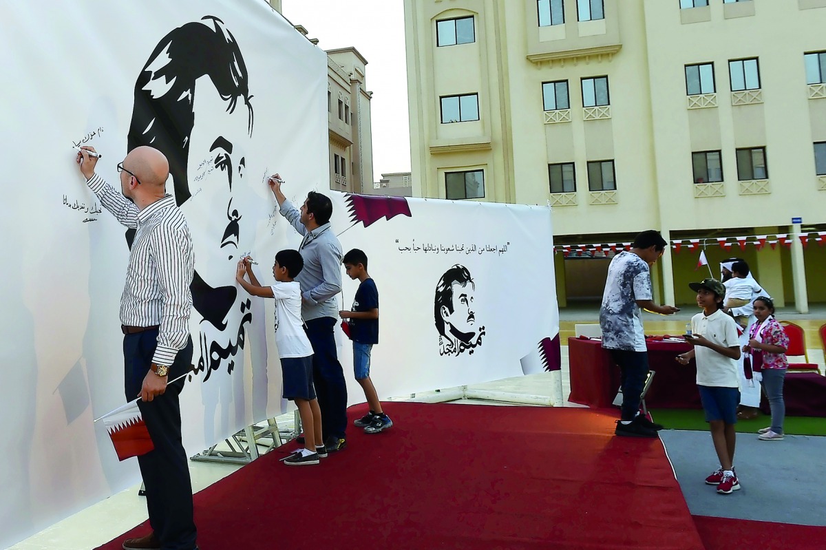 People write messages on 'Tamim Al Majd' murals at Ezdan Village 2 in Al Gharrafa yesterday.