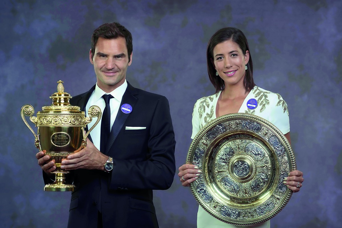 A handout composite picture taken on July 16, 2017 shows 2017 Wimbledon Men's and Women's singles champions, Switzerland's Roger Federer (L) and Spain's Garbine Muguruza posing with their trophies at the Champions Dinner in central London. AFP Photo / Ael