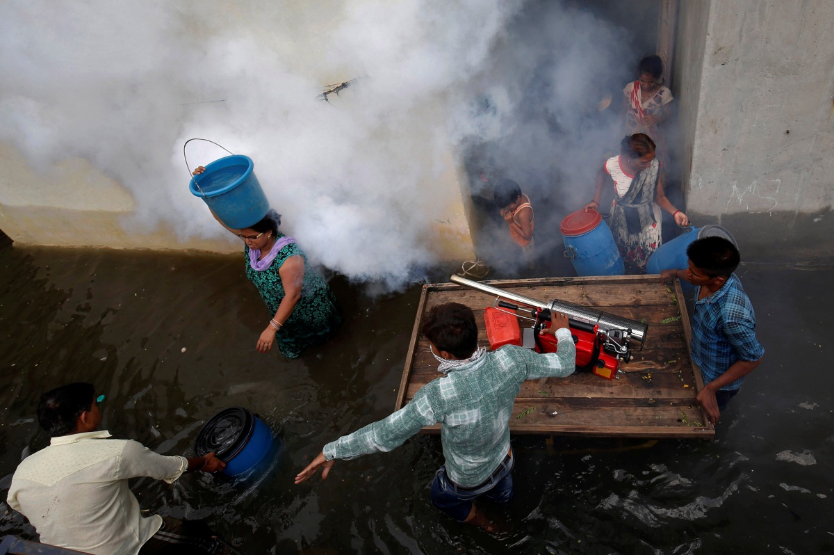 A municipal worker fumigates a flooded alley to prevent the spread of dengue fever and other mosquito-borne diseases, at a residential colony in Ahmedabad, India, July 29, 2017. Reuters/Amit Dave

