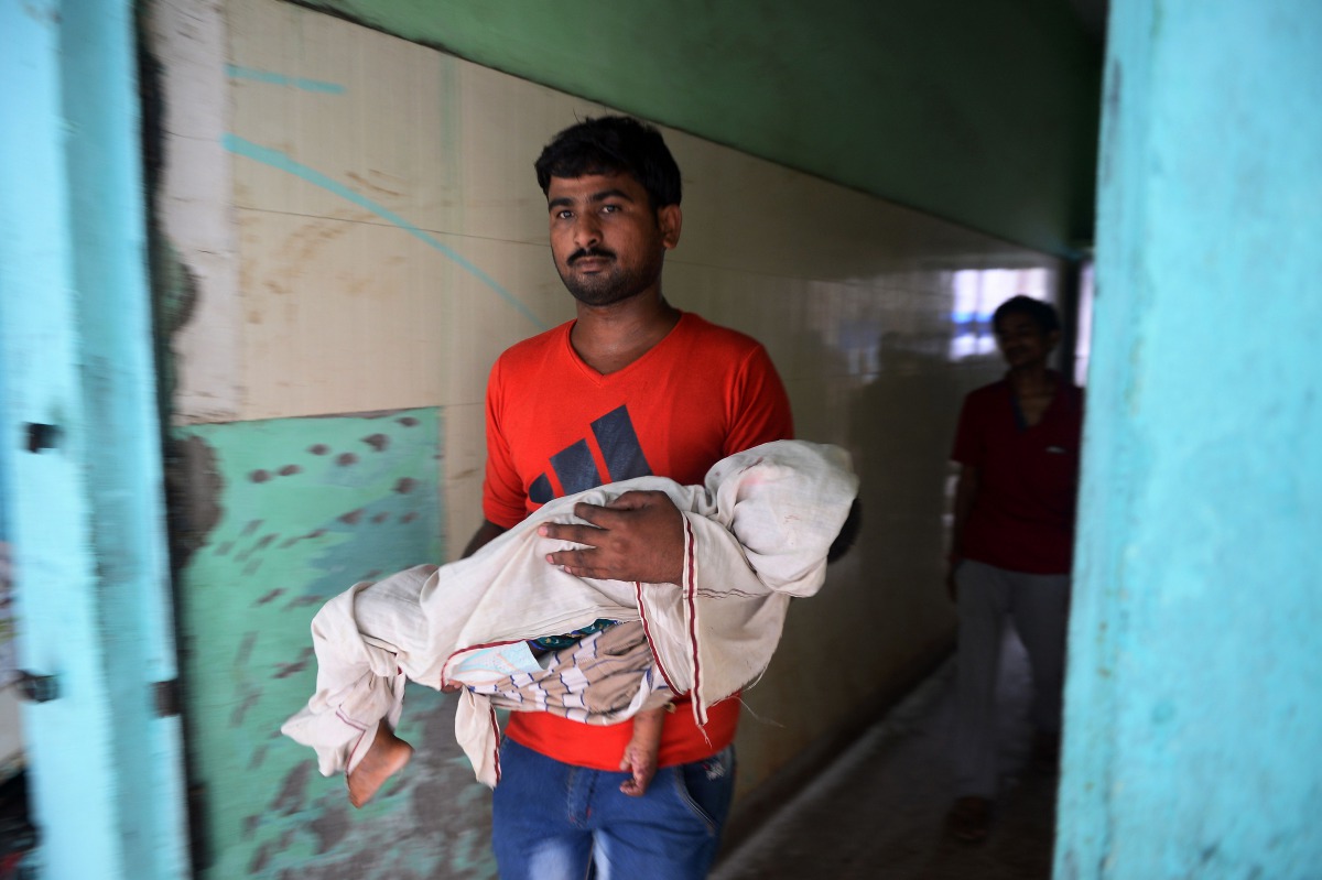An Indian relative holds the body of a child while walking out of Baba Raghav Das Hospital in Gorakhpur, in the northern Indian state of Uttar Pradesh, on August 13, 2017. AFP / Sanjay Kanojia