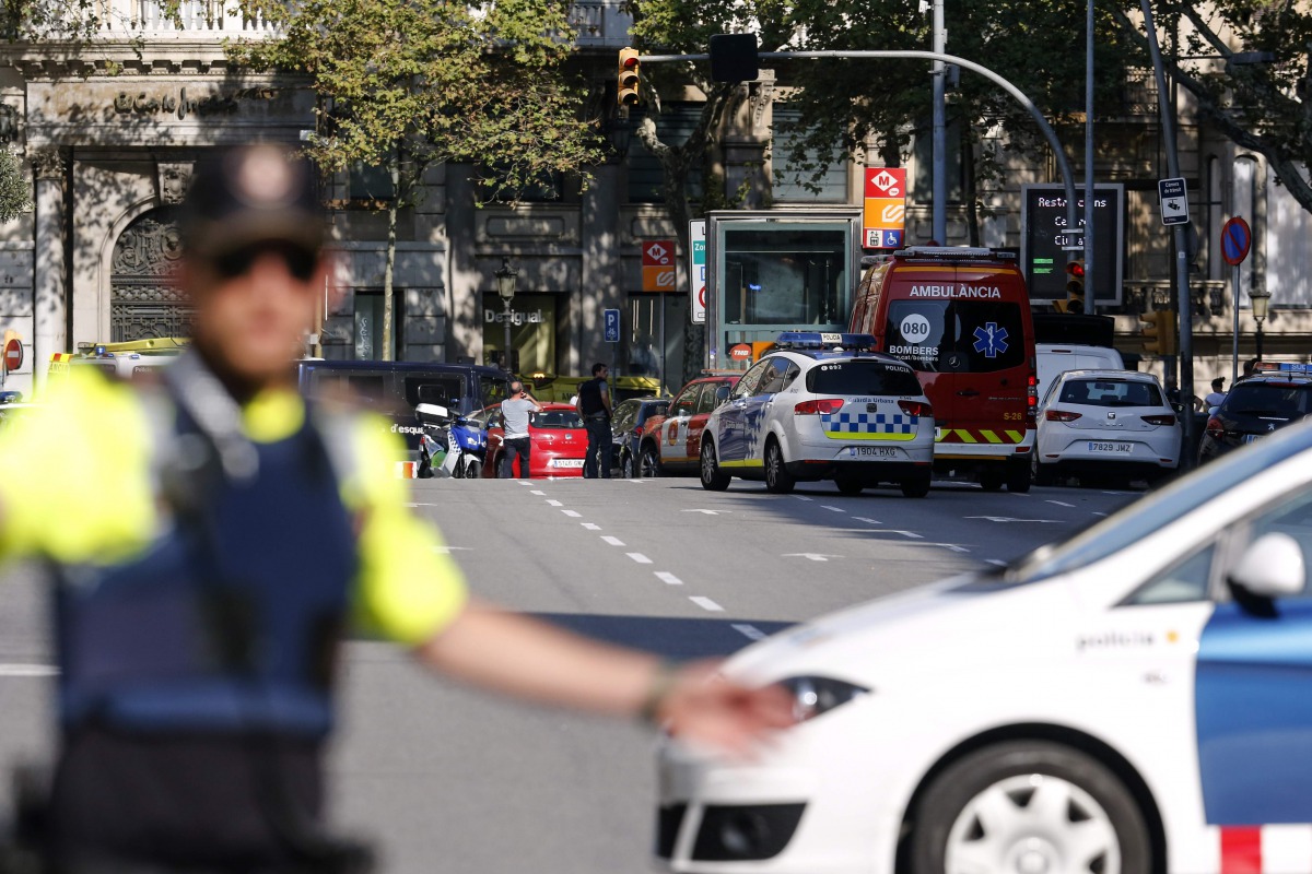 A policemen stand as he blocks the street to a cordoned off area after a van ploughed into the crowd, injuring several persons on the Rambla in Barcelona on August 17, 2017. / AFP / PAU BARRENA