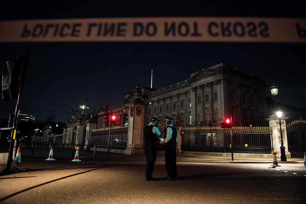 Police officers stand guard at a police cordon next to Buckingham Palace following an incident where a man armed with a knife was arrested outside the palace following a disturbance in London on August 26, 2017. / AFP.