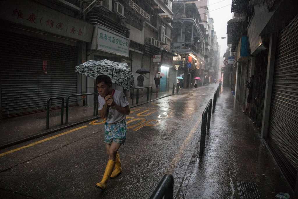 A man uses an umbrella during heavy rain as severe tropical storm Pakhar passes over Macau on August 27, 2017. / AFP.