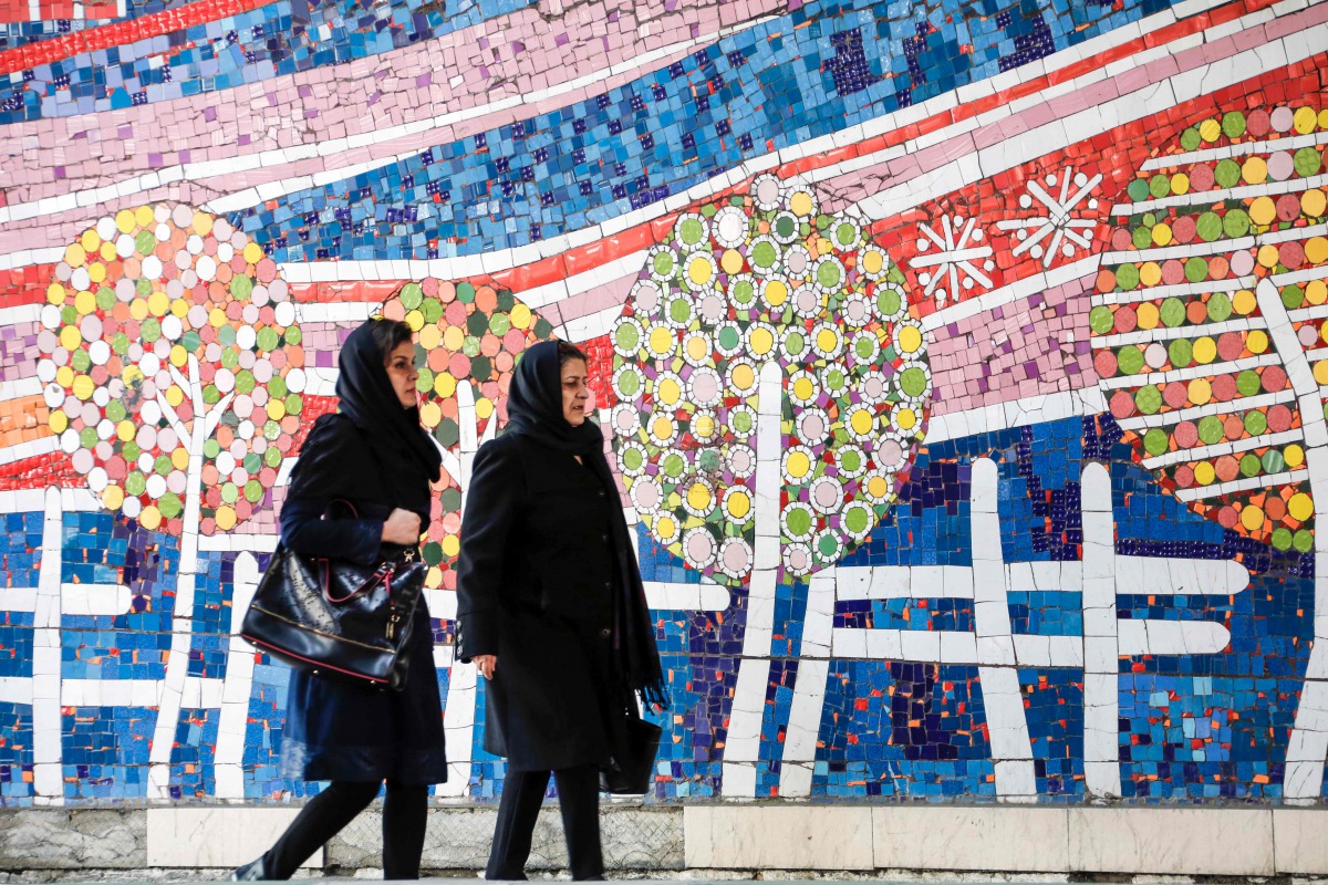 Two Iranian women walk along a street past a mosaic mural on Jaunary 14, 2017. (AFP / Atta Kenare) 