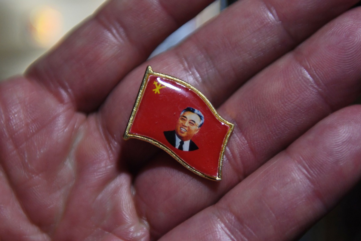 A Chinese vendor displays a pin with an image of North Korean founder Kim Il Sung, in the border city of Dandong, opposite the North Korean town of Sinuiju, in China's northeast Liaoning province on September 3, 2017. AFP / Greg Baker