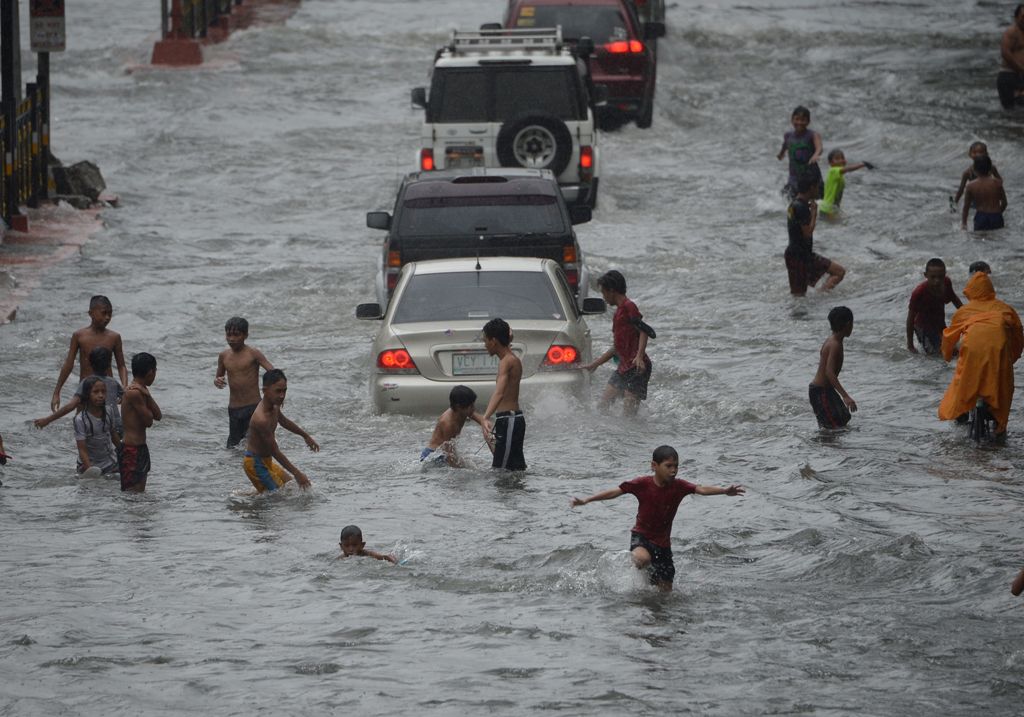 Young residents play on a flooded street in Manila on September 12, 2017, after tropical depression locally codenamed 