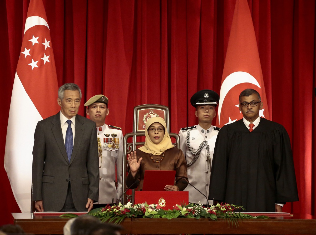 President-elect Halimah Yacob (C) takes the oath of office while flanked by Singapore Prime Minister Lee Hsien Loong (L) and Chief Justice Sundaresh Menon (R) during the presidential inauguration ceremony at the Istana Presidential Palace in Singapore Sep