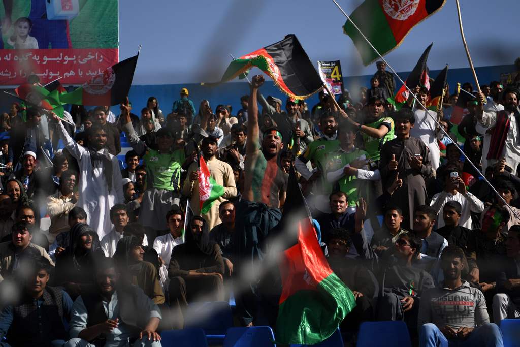 In this photograph taken on September 18, 2017, Afghan cricket fans cheer and wave the national flag during a match between Kabul Eagles and Band-e-Amir Dragons during the Shpageeza Cricket League T20 tournament at the Kabul International Cricket ground i