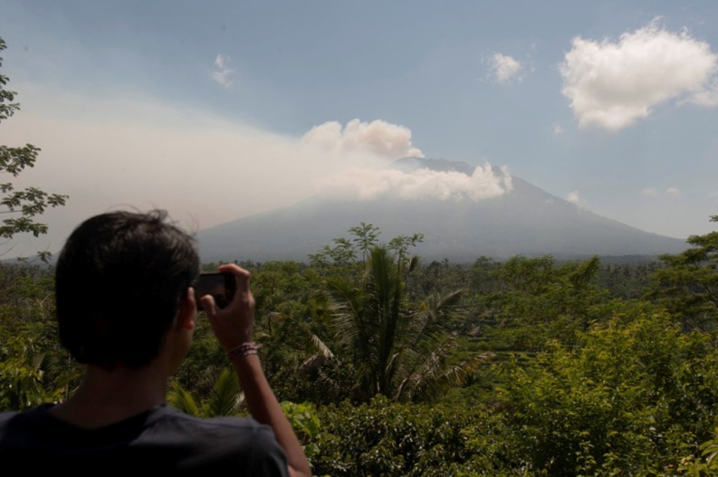 A local resident takes a picture of Mount Agung, an active volcano that authorities say is showing increased activity, from a monitoring station in Rendang Village, Karangasem on the resort island of Bali, Indonesia September 19, 2017. / Reuters.