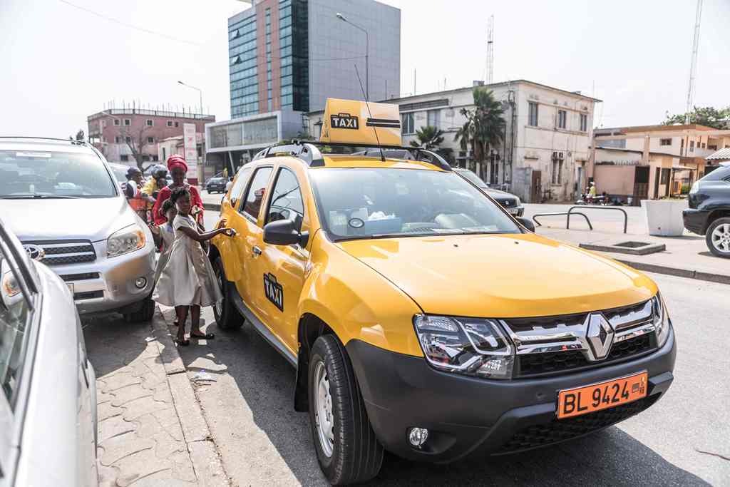 Schoolgirls get into a yellow Benin Taxi in Cotonou on September 18, 2017. AFP / YANICK FOLLY