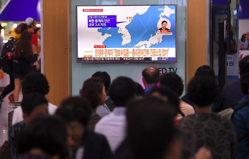 People watch a television news screen showing a map of the epicenter of an earthquake in North Korea, at a railway station in Seoul on September 23, 2017. AFP / JUNG Yeon-Je
