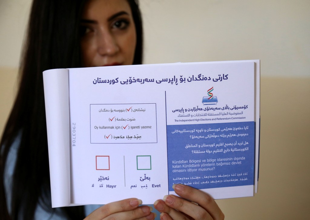 An employee from the Independent High Electoral Referendum Commission holds a voting ballot book at a voting station ahead of tomorrow's planned referendum for the Kurdistan region, in Arbil, the capital of the autonomous Kurdish region of northern Iraq, 