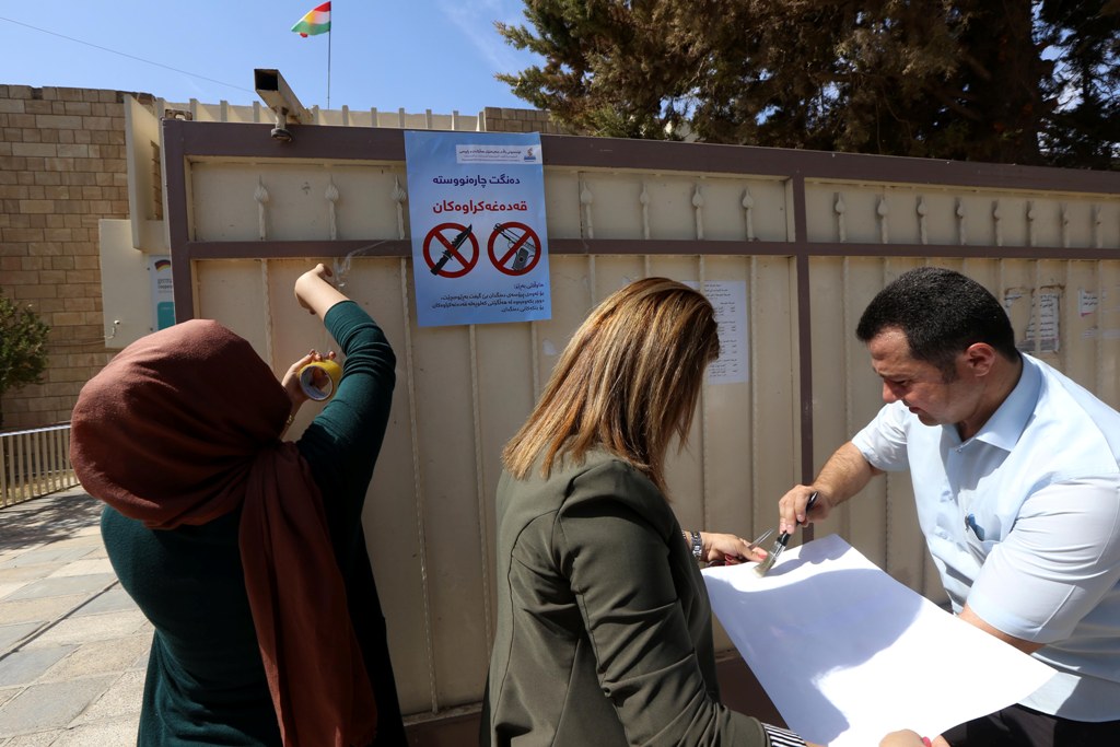 Employees from the Independent High Electoral Referendum Commission hang banners outside a voting station ahead of tomorrow's planned referendum for the Kurdistan region, in Arbil, the capital of the autonomous Kurdish region of northern Iraq, on Septembe