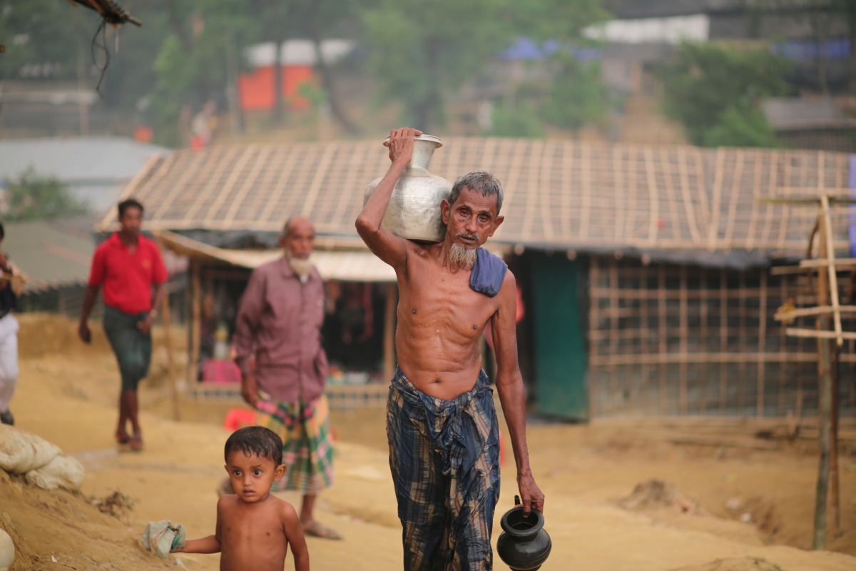 A Rohingya man, fled from oppression within ongoing military operations in Myanmar’s Rakhine state, walks through the mud along with a kid as they take shelter at a makeshift camp in Cox's Bazar, Bangladesh on September 24, 2017. (Zakir Hossain Chowdhury 