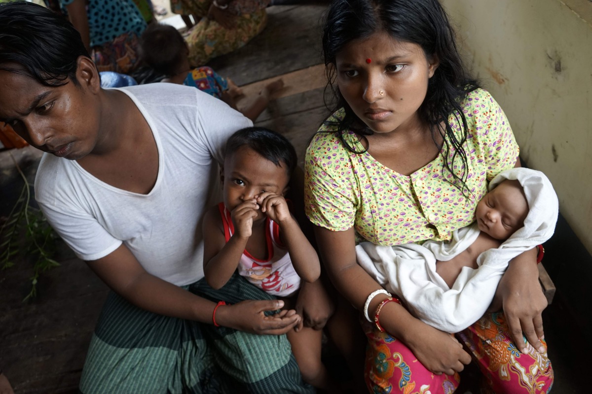 20-year-old Hindu girl, Chaw Shaw Chaw Thee (R) sits with her newborn baby, her husband and their young son at a shelter for refugees in Sittwe, on September 22, 2017. Chaw shaw Chaw Thee fears that twenty-three members of her family are dead, after Myanm