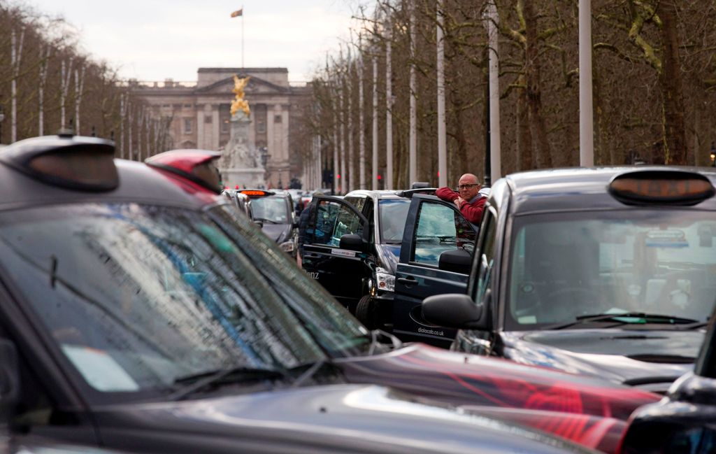 (FILES) This file photo taken on February 10, 2016 shows a driver standing by his vehicle as taxi drivers block The Mall as they demonstrate in central London on February 10, 2016 against UBER. AFP / JUSTIN TALLIS
