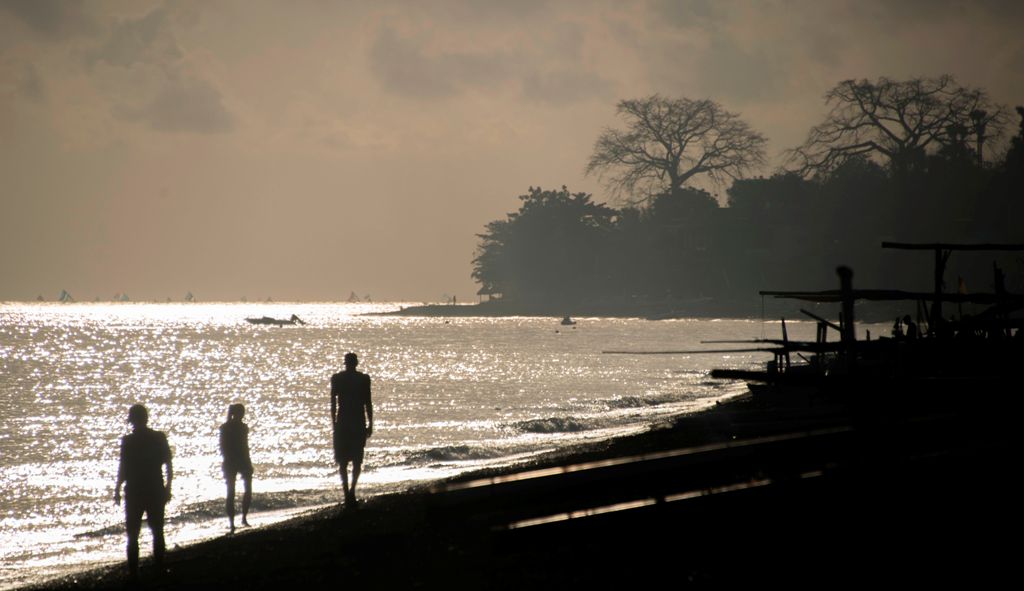 Tourists walk on Amed beach in Karangasem on the Indonesian resort island of Bali on September 30, 2017. AFP / BAY ISMOYO
