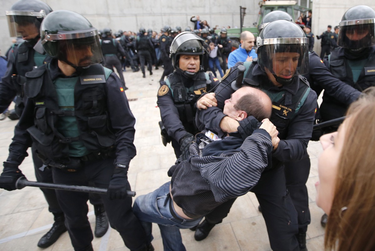 Spanish Guardia Civil guards drag a man outside a polling station in Sant Julia de Ramis, where Catalan president was supposed to vote, on October 1, 2017, on the day of a referendum on independence for Catalonia banned by Madrid.  AFP / Raymond Roig