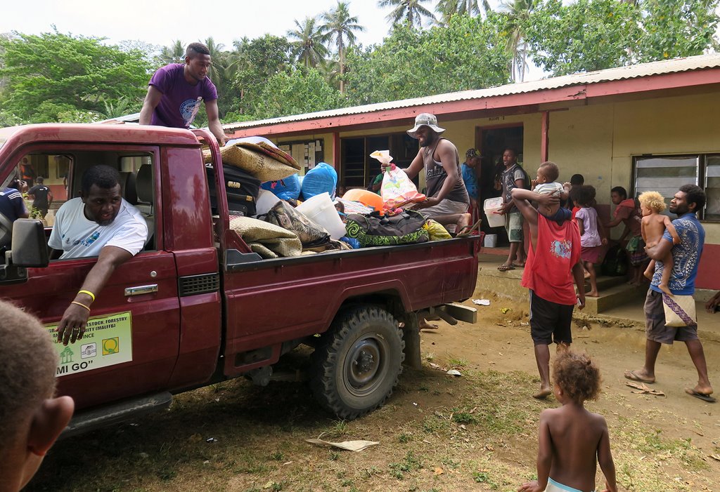 Residents who were evacuated due to the Manaro Voui volcano, look on as food is delivered to them at an evacuation center set up at the Ambae Bulu junior secondary school located in east Ambae, on Vanuatu's northern island of Ambae in the South Pacific, O