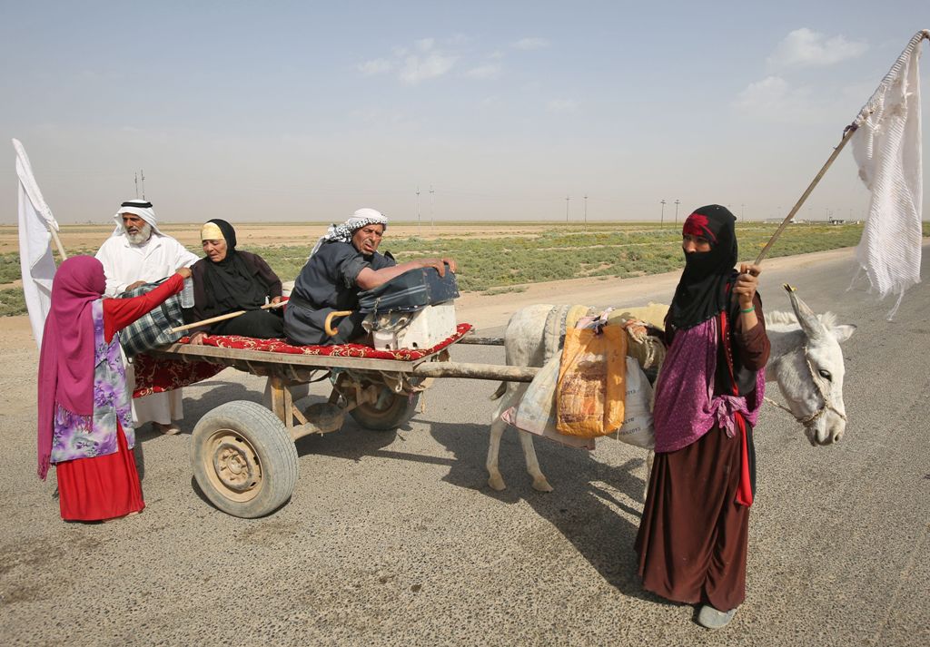 Members of an Iraqi family, displaced from the outskirts of Islamic State (IS) group stronghold Hawija (about 65 kilometres east of the northern city of Kirkuk), raise white flags while travelling with a donkey-cart on the road outside the town on October