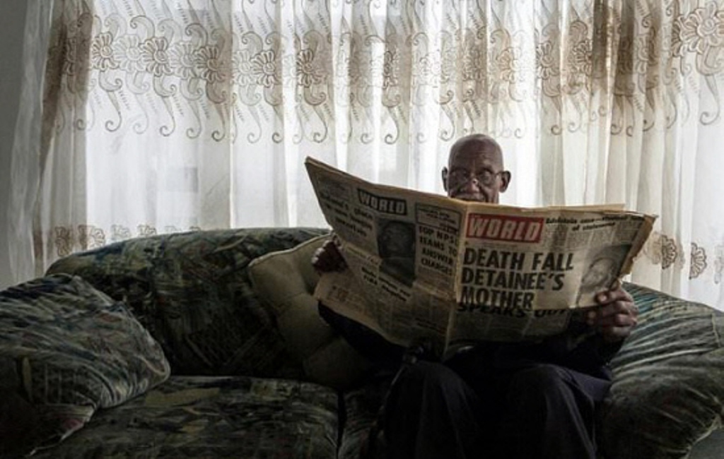 Phillip Mabelane, paging through a newspaper from the period, has been battling for 40 years for an investigation into the truth behind his son's 1977 death under apartheid./ AFP.