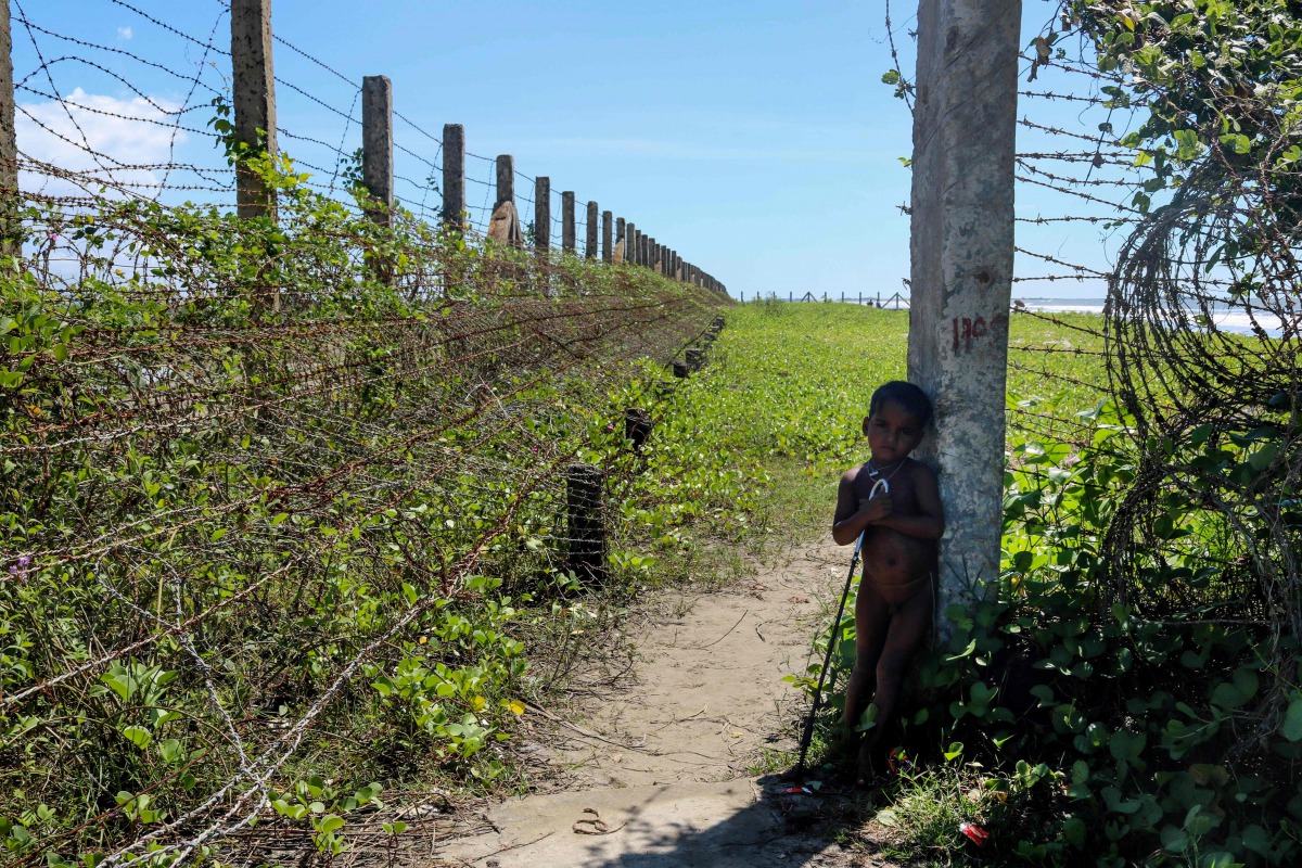This photo taken on October 10, 2017 shows a child stand next to a barbed wire fence along the Myanmar-Bangladesh border near the Du Thar Ya village in Maungdaw, Northern Rakhine State. AFP / Marion Thibaut