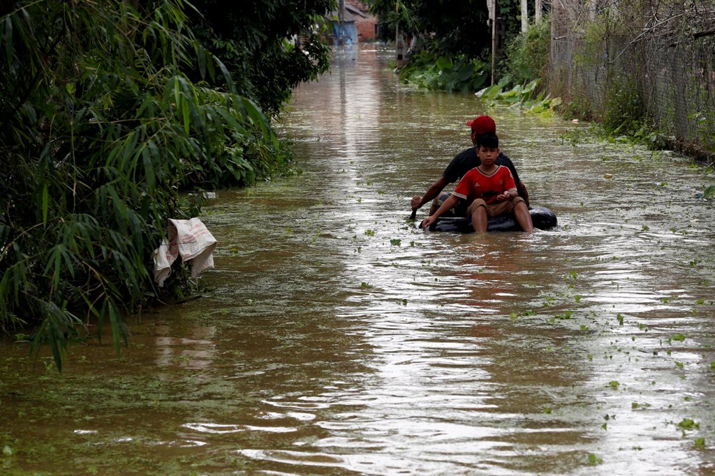 Boys paddle an improvised boat in a flooded village after a tropical depression in Hanoi, Vietnam October 13, 2017. REUTERS/Kham.