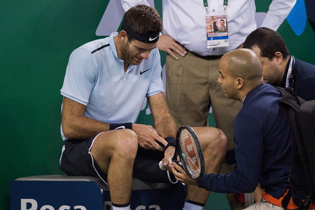 Juan Martin Del Potro of Argentina receives treatment after he fell during his men's singles quarter-final match against Viktor Troicki of Serbia at the Shanghai Masters tennis tournament in Shanghai on October 13, 2017. / AFP / NICOLAS ASFOURI
