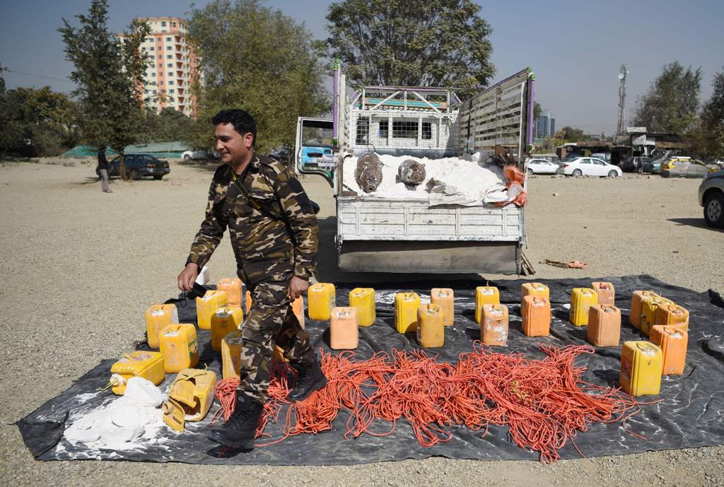 An Afghan security force personnel walks next to containers filled with explosive material after presenting to the media at the National Directorate of Security (NDS) headquarters in Kabul on October 15, 2017.  AFP / WAKIL KOHSAR
