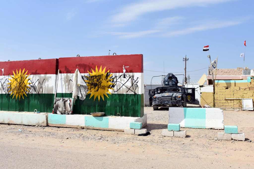 Iraqi army forces stand guard at a former Kurdish military position, bearing a defaced Kurdish flag, on October 13, 2017 in the northern Iraqi town of Taza Khurmatu, near Iraq's oil-rich multi-ethnic province of Kirkuk.  AFP / Marwan IBRAHIM
