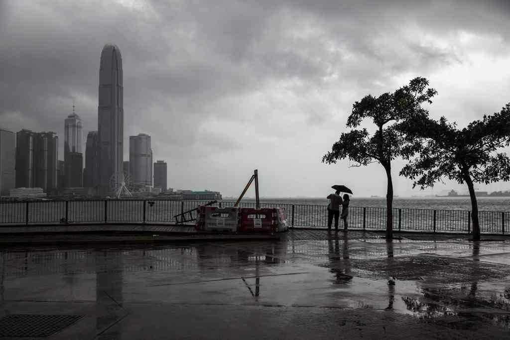 A couple uses an umbrella to shield themselves from the rain in Hong Kong on October 15, 2017 as Typhoon Khanun moves across the northern part of the South China sea. / AFP / DALE DE LA REY