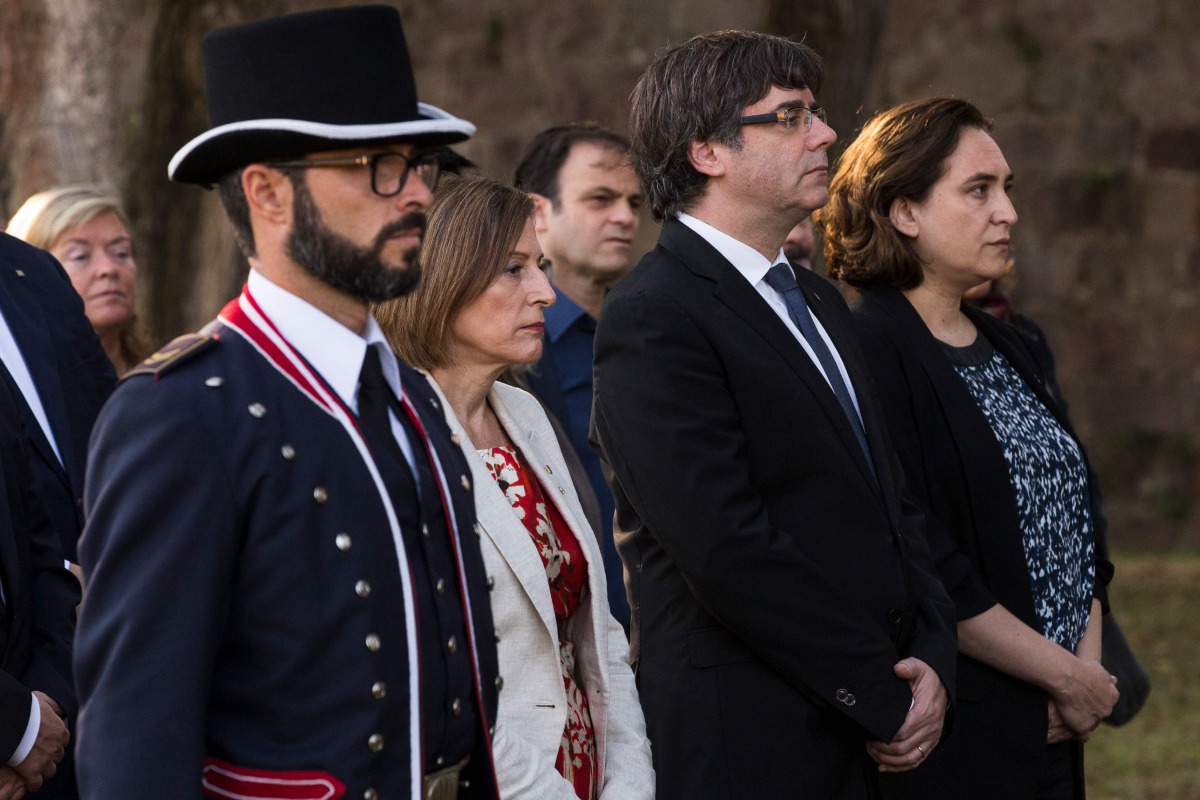 Catalan regional government president Carles Puigdemont (C), Catalan parliament president Carme Forcadell (L) and Barcelona mayor Ada Colau (R) pay their respects during a ceremony commemorating the 77th anniversary of the death of Catalan leader Lluis Co