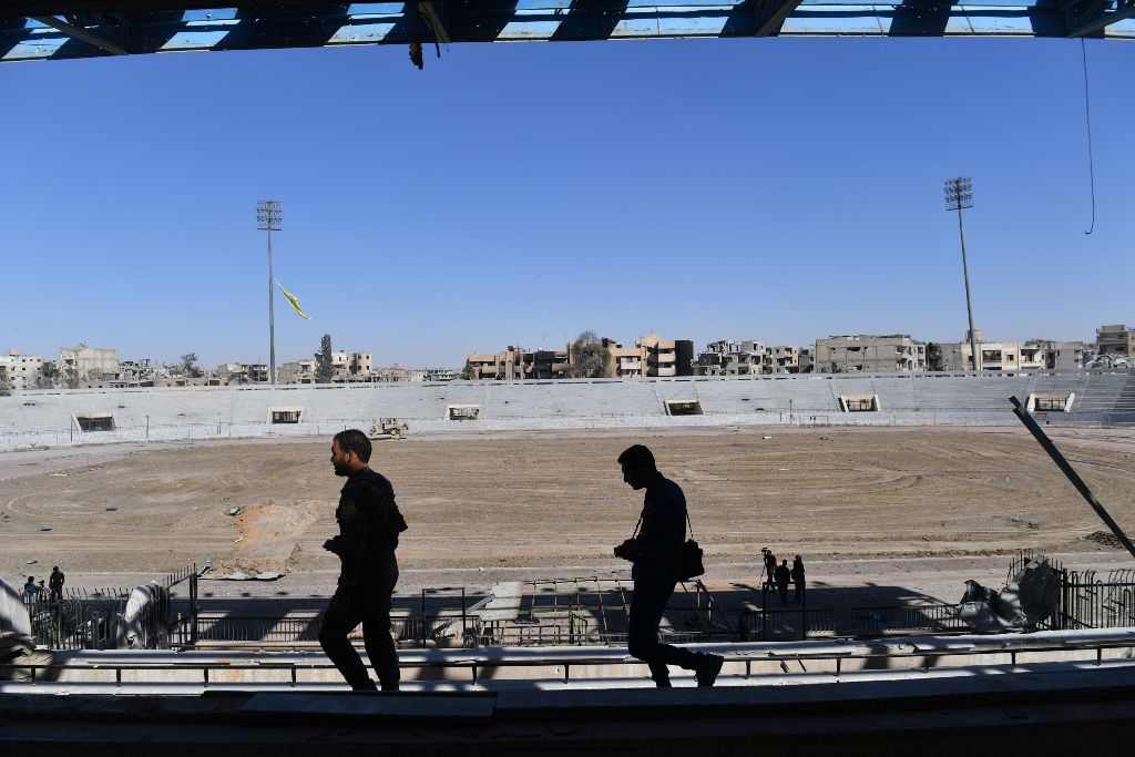 A member (L) of the Syrian Democratic Forces (SDF) inspects the municipal stadium in Raqa on October 18, 2017, after the US-backed forces retook the city from Islamic State (IS) group fighters.   AFP / BULENT KILIC
