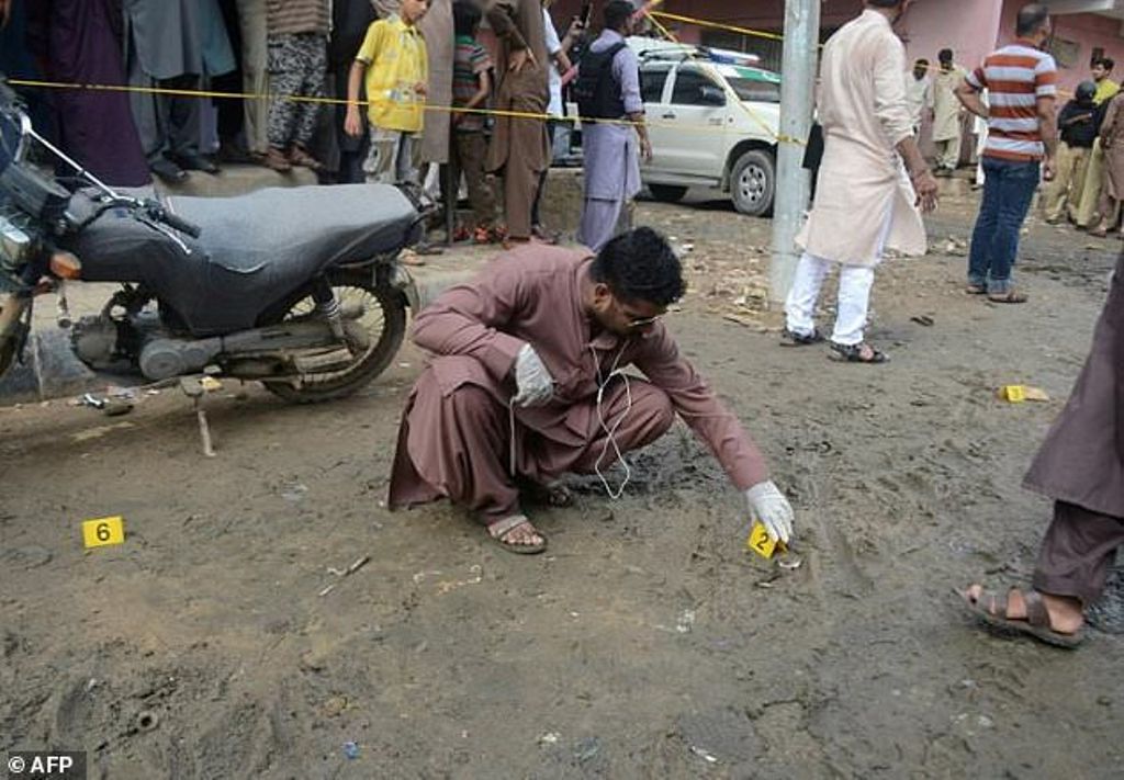 A Pakistani investigator inspects the scene of the attack on opposition politician Khawaja Izharul Hassan in Karachi in September