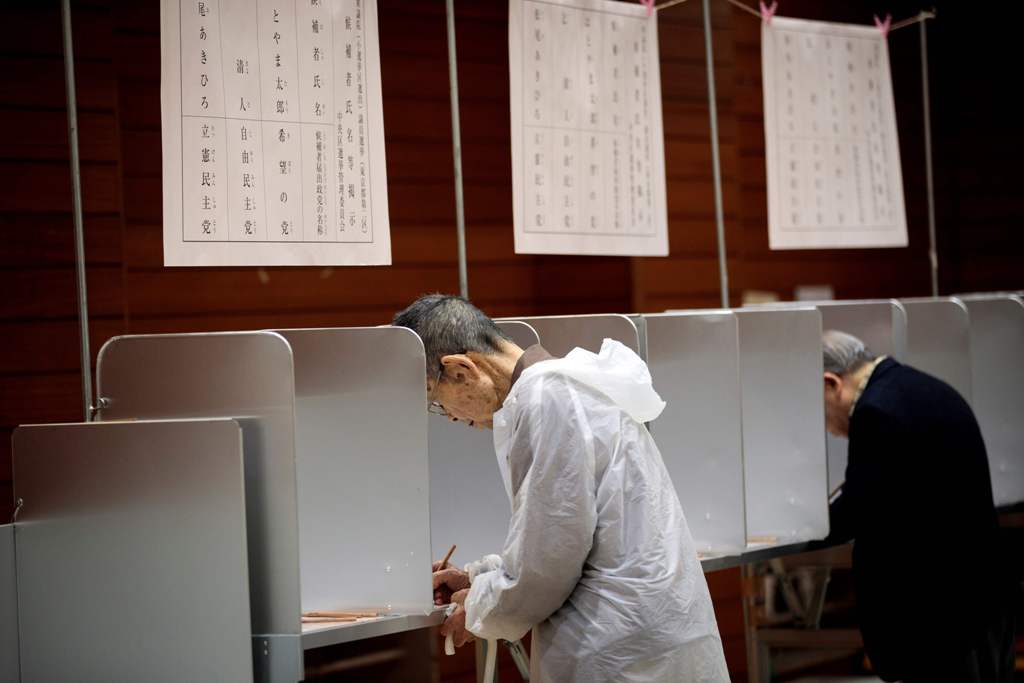 Voters fill in their ballot papers at a polling station to vote in Japan's general election in Tokyo on october 22, 2017.  AFP / Behrouz MEHRI
