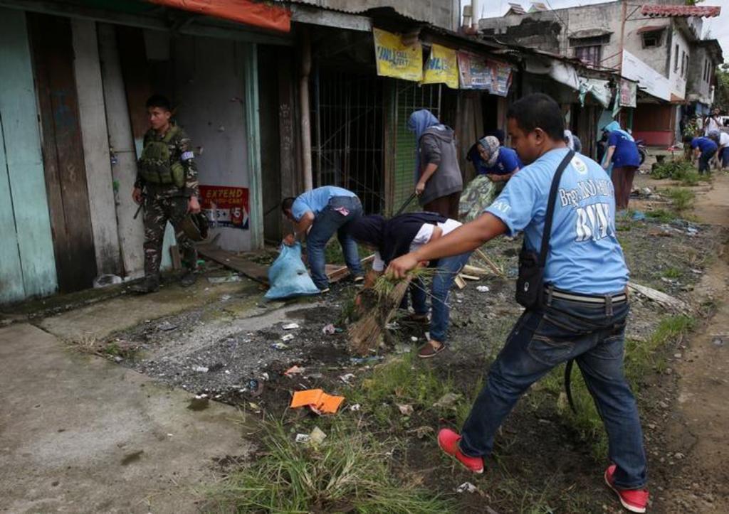 A soldier walks past members of the local government as they clear the area inside a war-torn Marawi city, southern Philippines October 19, 2017. REUTERS/Romeo Ranoco.