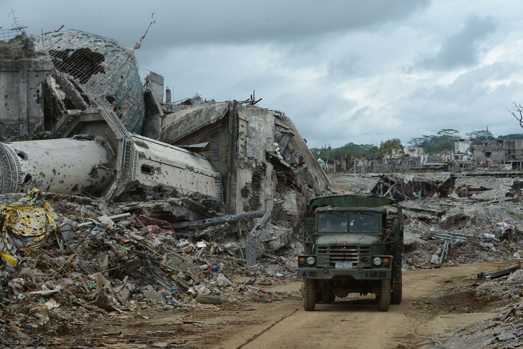 Military truck drives past the rubble of a bombed-out mosque in what was the main battle area in Marawi on the southern island of Mindanao on October 25, 2017, days after the military declared the fighting against IS-inspired Muslim militants over.  AFP /