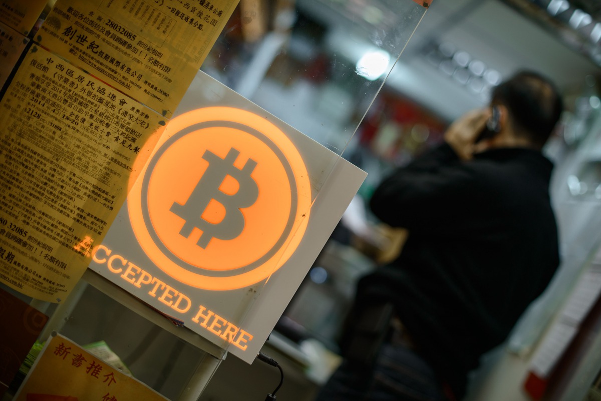 This file picture taken on February 28, 2014 shows a man talking on a mobile phone in a shop displaying a bitcoin sign during the opening ceremony of the first bitcoin retail shop in Hong Kong (AFP / Philippe Lo) 