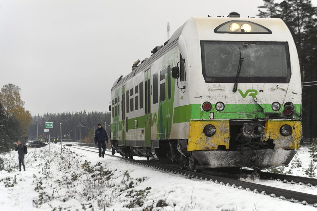 Passengers walk near the railroad crossing at the site of a crash between a train and a military truck on October 26, 2017 near Raseborg, southern Finland. / AFP.