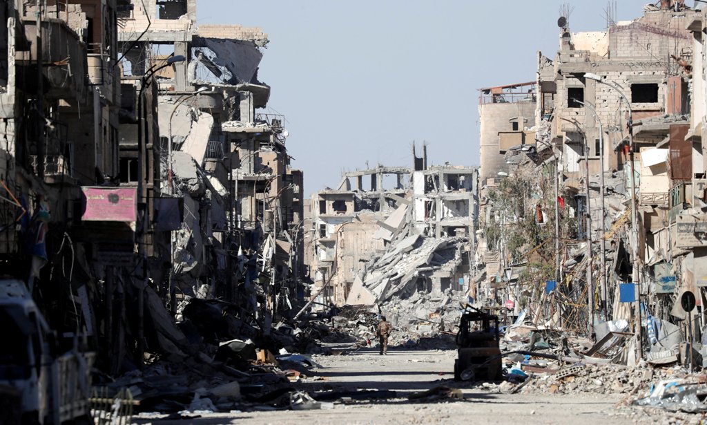 FILE PHOTO: A fighter of Syrian Democratic Forces stands amidst the ruins of buildings near the Clock Square in Raqqa, Syria October 18, 2017. REUTERS/Erik De Castro/File photo
