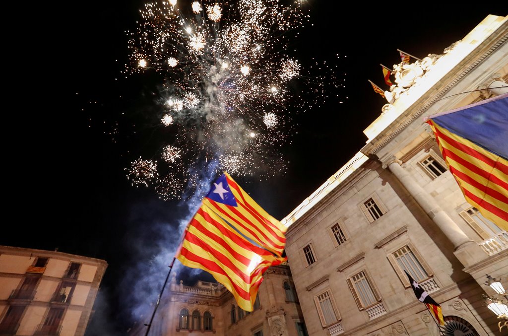 Catalan separatist flags are held up as fireworks go off in Sant Jaume Square in front of the Catalan regional government headquarters during celebratrions after the Catalan regional parliament declared independence from Spain in Barcelona, Spain, October