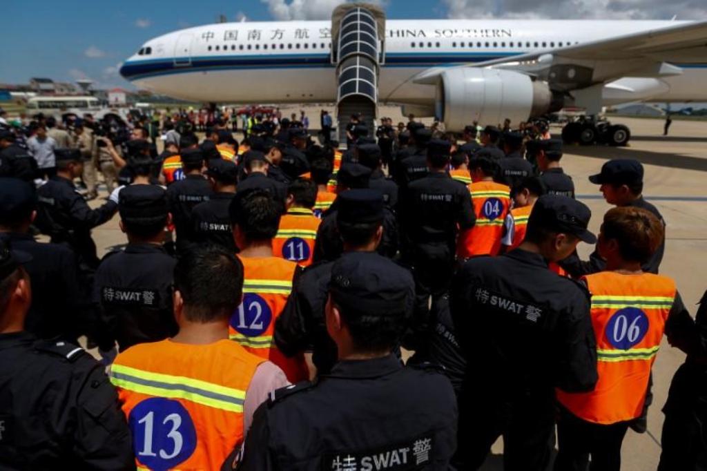 A file photo of Chinese nationals (in orange vests) who were arrested over a suspected internet scam, are escorted by Chinese police officers before they were deported at Phnom Penh International Airport, in Phnom Penh, Cambodia, October 12, 2017. REUTERS