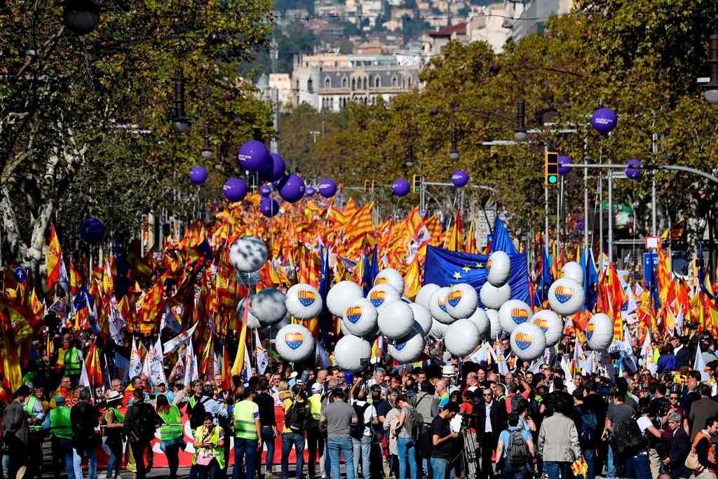 Protesters wave Spanish flags and hold balloons bearing a heart-shaped collage of the Spanish, Catalan Senyera and EU flags during a pro-unity demonstration in Barcelona on October 29, 2017.  AFP / LLUIS GENE
