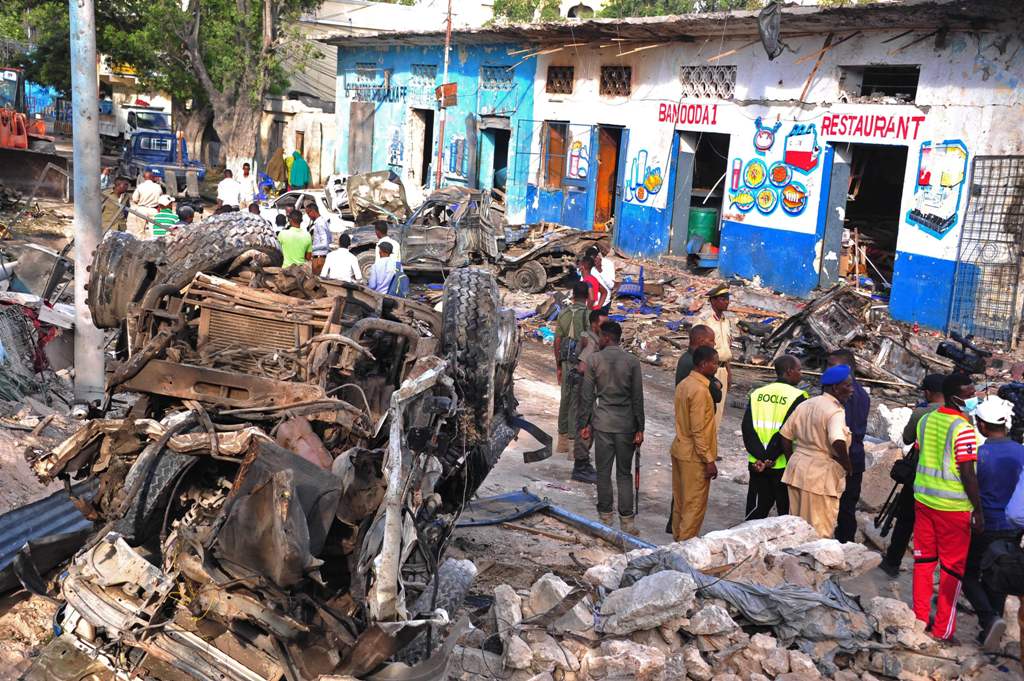 Residents walk at the scene of a blast on October 29, 2017, a day after two car bombs exploded in Mogadishu. AFP / Mohamed ABDIWAHAB
