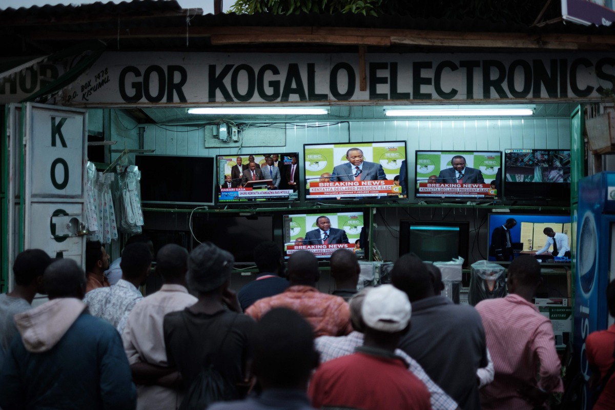 People watch live broadcast as Uhuru Kenyatta is declared the winner following presidential re-election results by Kenya's Independent Electoral and Boundaries Commission (IEBC) on TV at a local electrical shop in Kisumu, on October 30, 2017.  AFP / Yasuy