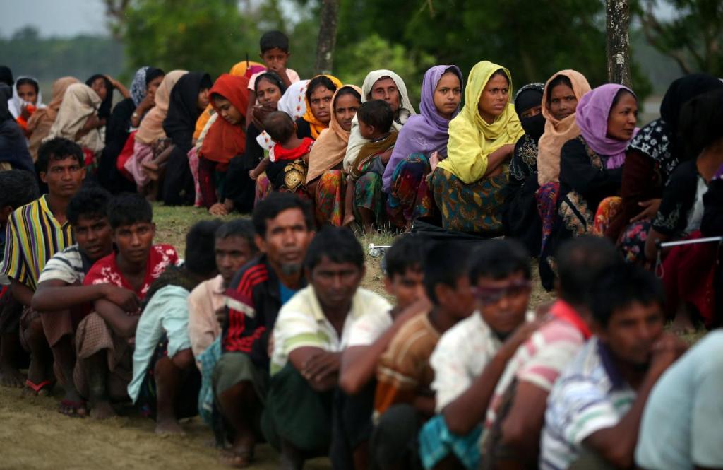 Rohingya refugees sit in a line as they wait to receive permission from the Bangladeshi army to continue their way after crossing the Bangladesh-Myanmar border, at a port in Teknaf, Bangladesh, October 31, 2017. REUTERS/Hannah McKay.